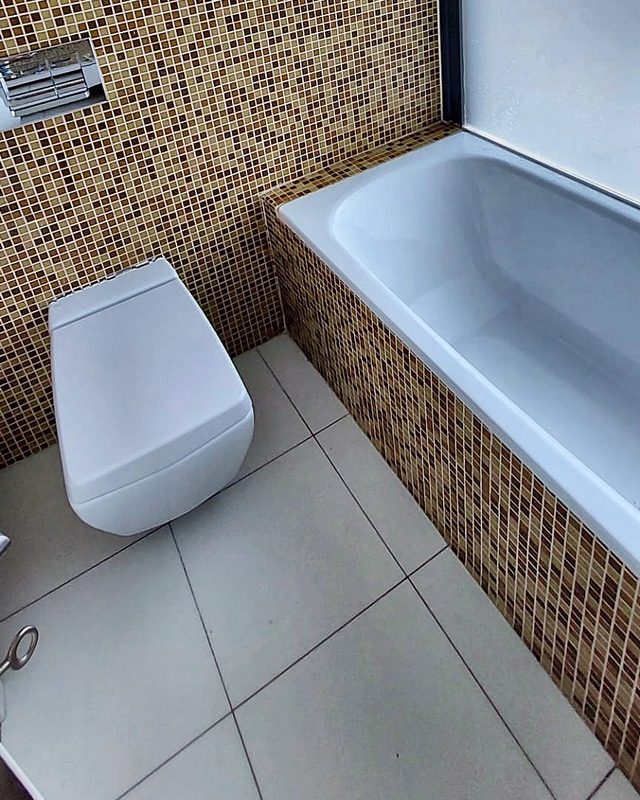 Room A's en-suite bathroom with a bathtub, mosaic tiles and a wall-hung toilet