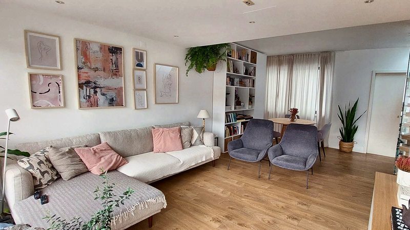 Sofa corner with cushions, art on the wall and armchairs by the window