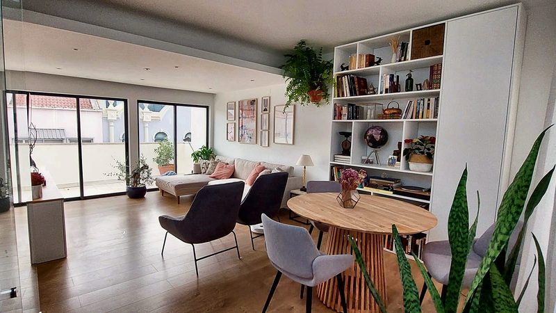 Living room with sofa, round dining table, bookshelf and glass doors to the terrace
